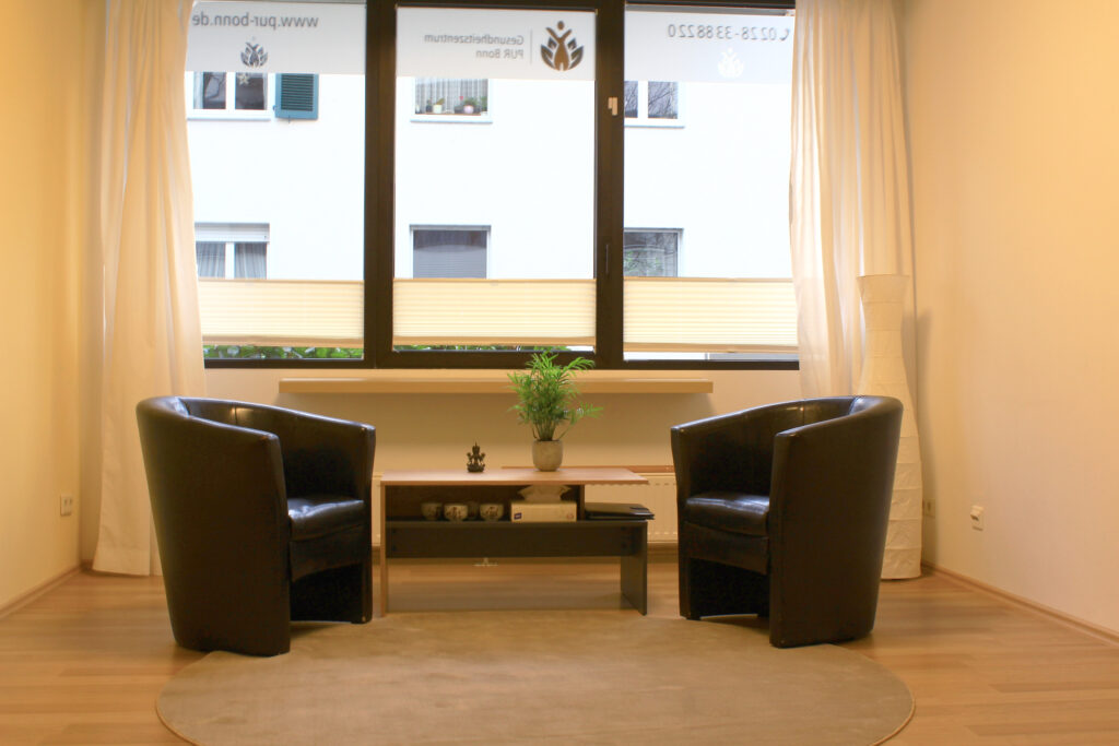 Die Praxis; zwei dunkle Kunstledersessel und ein kleiner Tisch
