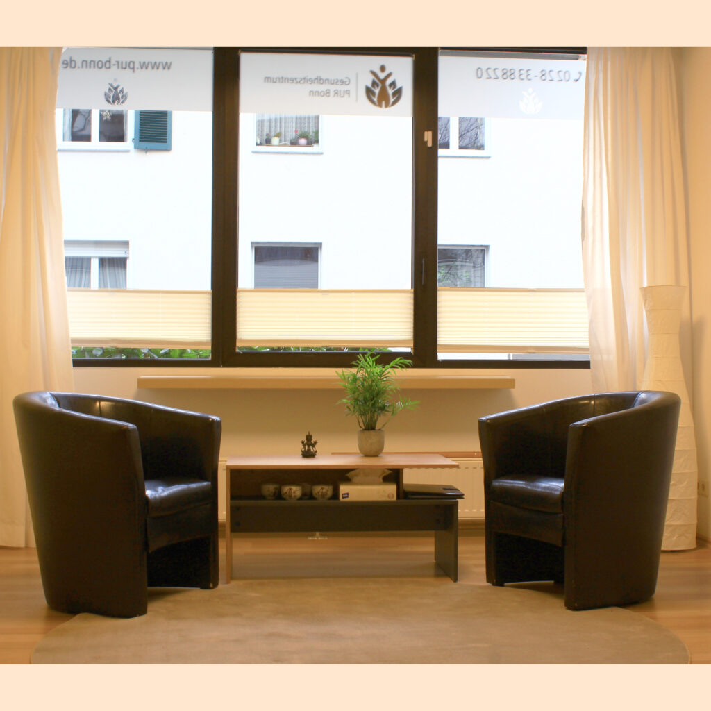 Die Praxis; zwei dunkle Kunstledersessel und ein kleiner Tisch